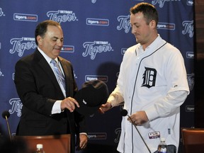 Detroit Tigers general manager Al Avila, left, hands a hat to pitcher Jordan Zimmermann during the news conference in Detroit, Monday, Nov. 30, 2015.