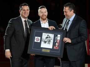 Former Spitfires captain Ryan Ellis, centre, is presented a picture by team president Bob Boughner, left, and general manager Warren Rychel.