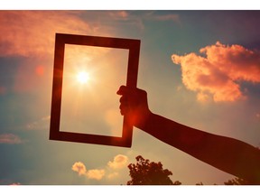 Hand holding a wooden frame on sunrise sky background. Painting concept. Image by fotolia.com.