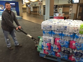 Spitfires staffer Nathan Sellon poses for a photo while loading donated water bottles destined for the town of Flint, Mich., on Jan. 22, 2016, in Windsor. Windsorites have donated some 50,000 bottles of water in response to a call by the city's junior hockey team. The Windsor Spitfires launched the water drive Thursday during a game against the Flint Firebirds.