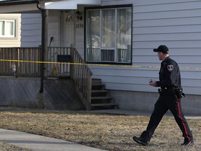 A Windsor police officer walks in front of a house at 1596 Aubin Rd. where 52-year-old John Jubenville was murdered on Saturday, March 23, 2013.