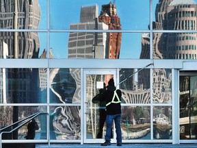 A window washer works on the downtown Chrysler building on Friday, January 29, 2016, as the Detroit skyline is reflected on a sunny day.