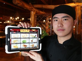 Jordy Lin, co-owner of Taka Japanese Sushi and Thai Food Restaurant, holds one of the restaurant's iPads which customers use to order their meal. Items are prepared fresh and are quickly delivered to table.