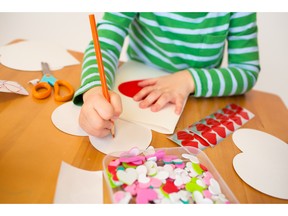 A child creates Valentine's Day arts and crafts with hearts, pencils and paper. Photo by fotolia.com.