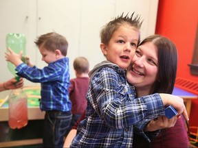 Jessica Szucki, right, visits with her autiistic children Dryden and Cooper, left, while her other son Lennon plays in the background Monday at the Summit Centre for Preschool Children with Autism on Prince Road. Intensive therapy is having a big impact on many of the autistic kids.