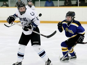 Ursuline Lancers' Sam Anderson, left, and St. Anne Saints' Riley Pirouet watch a bouncing puck in the third period of the SWOSSAA 'AAA' girls hockey final at Erickson Arena in Chatham, Ont., on Monday, Feb. 29, 2016.