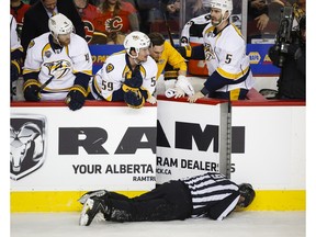 Nashville Predators' players look over the bench at linesman Don Henderson after he was hit by Calgary Flames' Dennis Wideman during second period NHL hockey action in Calgary, Wednesday, Jan. 27, 2016.THE CANADIAN PRESS/Jeff McIntosh