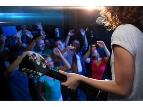Woman singing and playing guitar to a happy crowd. Photo by fotolia.com.