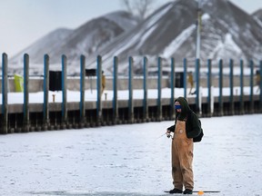 A man ice fishes at the Lakeview Park Marina in Windsor, Ont. on Tuesday, Feb. 16, 2016.