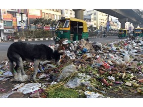 Traffic passes by a pile of garbage following a strike by municipal workers in New Delhi on February 1, 2016. Rubbish piled up on New Delhi's streets on February 1 as refuse collectors vowed to push ahead with a nearly week-long strike, the latest crisis to hit the world's most polluted city.