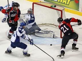 The Windsor Spitfires Logan Brown (right) fans a shot in front of  teammate Christian Fisher and the Sudbury Wolves Dmitry Sokolov and goaltender Troy Timpano at the WFCU Centre in Windsor on Thursday, Feb. 4, 2016.