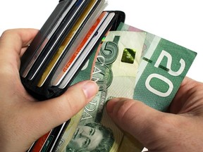 The action of pulling canadian money out of a wallet. Credit: Fotolia.