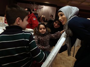Dania Khalife (right) greets Syrian family Ousama, Saja and Manar El-Hariri (left to right) as they attend a benefit dinner for Syrian families at the Caboto Club in Windsor on Friday, February 12, 2016.