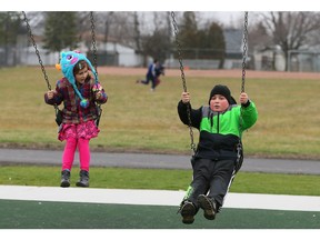 Windsor, Ontario. December 30, 2015. Peyton Hearn, 6, left, swings with her brother Ethan Ellwood, 11, at Remington Park playground on Dec. 30, 2015.  Warm temperatures have area residents enjoying traditional fall and summer activities. (NICK BRANCACCIO/Windsor Star)