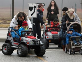 Local Syrian refugees Maher Alumar, left, with sons, Ibrahem and Ammar, get their first taste of Windsor roads and Windsor's emergency service personnel at The Safety Village, Monday March 14, 2016. Behind, Windsor Police Constable Cealia Gagnon, directs traffic as other families have experience the simulated roadway. (NICK BRANCACCIO/Windsor Star)