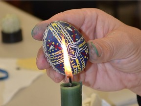 A candle flame is used to melt the wax off an egg to reveal the multi-coloured pattern at Amherstburg's Gibson Gallery on March 12, 2016.