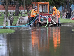 Rob Switzer (L) and Ken Major work at the Windsor Grove cemetery on Monday, March 28, 2016, dealing with flood conditions after heavy rains on Sunday.