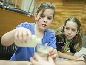 Jacee Zimmer, 9, left, and Kitti Keller, 10, pour dirty water through a filter made of sand and rocks at the Ed Lumley Centre for Engineering Innovation where Girl Guides are earning their engineering, science, and water badges, Satrurday, March 12, 2016.