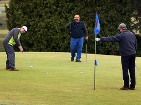 Mike Palenchar (left) looks to sink a 16-foot putt at Orchard View Golf Club on March 9, 2016. Rob Smith and Tom Steinke (right) look on. The Windsor-Essex region had its warmest March 9 on record.