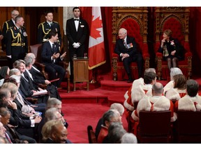 Windsor native and Chief Page Ali Boussi stands between Prime Minister Justin Trudeau and Gov. Gen. David Johnston as they wait for the speech from the throne in the Senate Chamber on Parliament Hill in Ottawa on Dec. 4, 2015.
