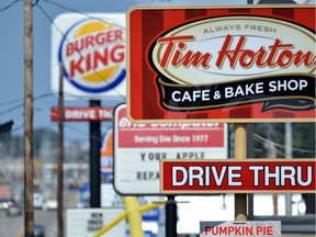 Signs for a Tim Hortons restaurant, foreground, and a Burger King restaurant are displayed along Peach Street Tuesday, Aug. 26, 2014, in Erie, Penn. Burger King struck an $11 billion deal to buy Tim Hortons that would create the world's third largest fast-food company and could make the Canadian coffee-and-doughnut chain more of a household name around the world.
