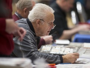 John Grooms, 72, looks for stamps missing from his collection while at WINPEX, hosted by the Essex County Stamp Club at the Caboto Club, Saturday, March 12, 2016.