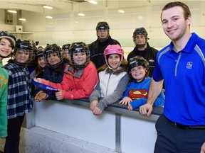 Tyler McGregor, right, lets a group of children hold his gold medal from the 2013 world sledge hockey championships on March 22, 2016 at Central Park Athletics in Windsor.