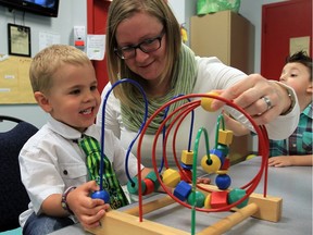 Wearing his St. Patrick's Day tie, Nico, 3, is assisted by registered early childhood educator Wendy Oakey at ABC Day Nursery on Lauzon Road on March 17, 2016.