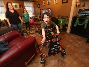 Kim Chapieski watches as her son Liam uses a walker to get around at his East Windsor home on March 9, 2016. Liam, 6, has a severe form of cerebral palsy. His sister Sienna looks on.