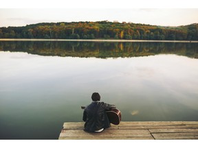 Young man playing guitar at the lake. Photo by fotolia.com.