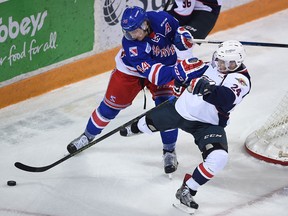 Kitchener Rangers player #44 Frank Hora, left, checks Windsor Spitfires player #24 Mads Eller behind the Rangers net in first period action.