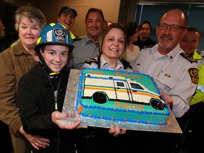 Parker Ouellette, left, holds his birthday cake along with Essex-Windsor EMS Deputy Chief Chris Grant and EMS Chief Bruce Krauter, right, during a celebration for Parker's 13 acts of kindness for emergency personnel.  Parker, 13, was joined by family members and about a dozen paramedics for a pizza lunch and presentation by Chief Krauter.