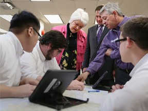 Ontario Minister of Education Liz Sandals visits with students from Assumption College Catholic School along with vice principal Doug Sadler, and robotics, manufacturing and aerospace teacher Mike Costello during a visit in Windsor, Ontario. The minster announced that the Windsor Essex Catholic District School Board will receive funding for school consolidation at several schools.
