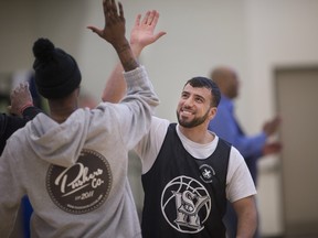 Chaouki Hamka, from the South West Detention Centre, gets a high five from Windsor Express player, Brandon Robinson, after Hamka hit a half-court shot during a three point contest during the Law Enforcement Basketball Tournament at the South West Detention Centre, Saturday, April 9, 2016.