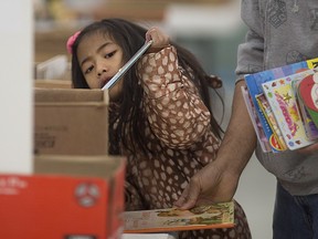 Christel Gaoiran, 6, looks through children's books with her father, Charlie Gaoiran, at the Raise-a-Reader book sale at Devonshire Mall, Sunday, April 10, 2016.