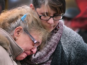 Dee Dee Krug comforts her mother Rose Anne Seremach at a ceremony for the day of mourning for fallen workers on Thursday, April 28, 2016, at the Coventry Gardens in Windsor.