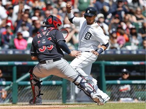 Detroit Tigers' Victor Martinez, right, avoids Cleveland Indians catcher Roberto Perez (55), waiting for the throw, on his way to scoring on a Nick Castellanos two-run single in the fourth inning Sunday, April 24, 2016, in Detroit.