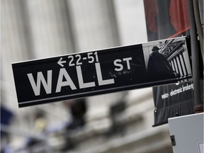 This Oct. 2, 2014, photo, shows a Wall Street sign adjacent to the New York Stock Exchange.