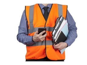 Man in orange visibility vest carrying folders and phone. Photo by fotolia.com.