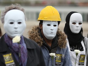 Wearing masks to represent workers killed on the job, a group of people take part in the National Day of Mourning at Dieppe Park in 2012.   This year's event takes place Thursday, Apr. 28. (DAX MELMER/The Windsor Star)