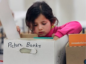 Holli Dugan, 6, hunts for a book during the Raise-a-Reader sale on April 16, 2016 at Devonshire Mall.