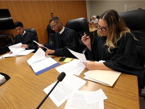 Students Mike Cervini, Jeremiah Bowers and Madison Ziolli (left to right) review their notes during a mock trial competition between Holy Names and Leamington District High School at Superior Court in Windsor on Thursday, April 21, 2016.