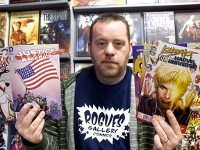 Shawn Cousineau, owner of Rogues Gallery Comics, holds up donated comic books for the fifth annual Goodfellows Comic Book Drive in his store Sunday, Nov. 10, 2013.