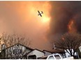 Smoke fills the air as a small plane flies overhead in Fort McMurray, Alta., on Tuesday May 3, 2016.