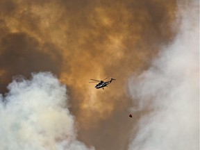 A helicopter battles a wildfire in Fort McMurray, Alta., on Wednesday May 4, 2016. The wildfire has already torched 1,600 structures in the evacuated oil hub of Fort McMurray and is poised to renew its attack in another day of scorching heat and strong winds.