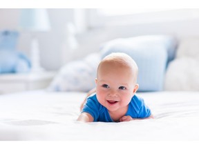 Baby boy in white sunny bedroom. Photo by Getty Images.