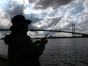 An unidentified man casts his fishing rod into the Detroit River in this 2014 file photo.