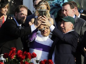 Mario Gutierrez, middle, trainer Doug O'Neill, left, and horse owner J. Paul Reddam of Windsor hold the trophy after Gutierrez rode Nyquist to victory in the 142nd running of the Kentucky Derby horse race at Churchill Downs Saturday, May 7, 2016, in Louisville, Ky.