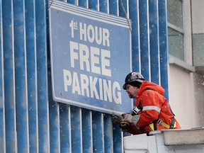 A worker prepares to remove the '1st Hour Free Parking' sigh from the municipally-owned parking garage at Goyeau and Chatham Street in downtown Windsor on Jan. 4, 2016.