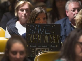 A woman holds a sign urging trustees to not close Queen Victoria school during Tuesday's meeting of the Greater Essex County District School Board.